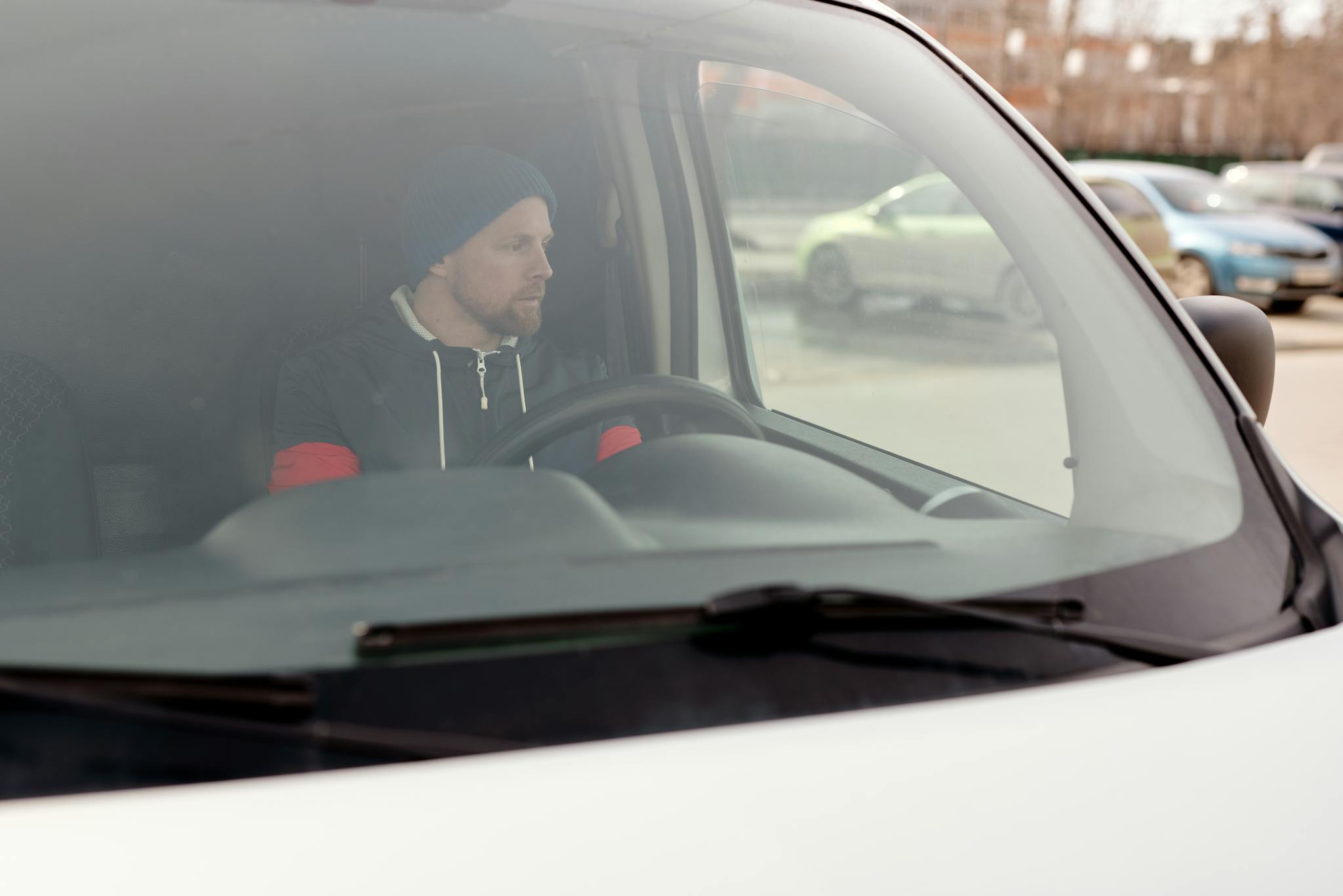 Man sitting in a van, focused on driving in an urban setting.