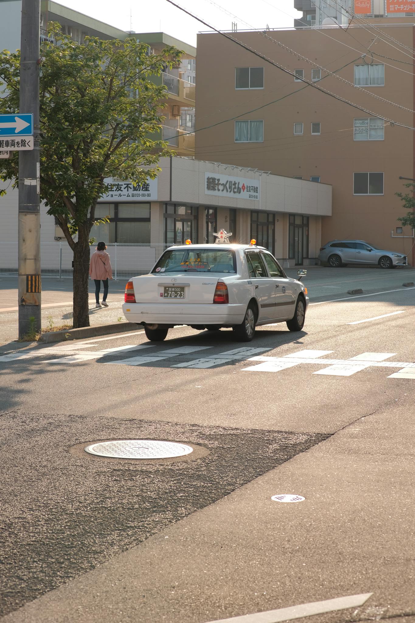 White taxi on a calm city street during the day, showcasing urban life.